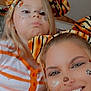 Kara is registered to the contest to win money with this photo: animal_ears, child, closeup, costume, cute, face_paint, friends, fun, happy, indoor, orange, people, playful, portrait, pout, smile, striped_clothing, tiger_ears, white, woman