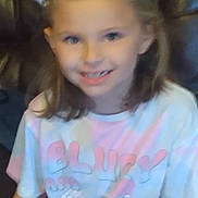 Kara is registered to the contest to win money with this photo: bow, cartoon, casual, child, clothing, couch, cute, furniture, girl, hair_accessory, happy, home, indoor, person, portrait, relaxed, sitting, smiling, tshirt, young