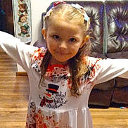 Kara is registered to the contest to win money with this photo: child, girl, smiling, dress, hair_clips, arms_outstretched, indoor, living_room, wooden_floor, couch, holiday_theme, snowman, long_hair, cute, portrait, happy, person, furniture, home, casual