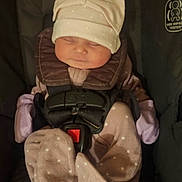 Alice is registered to the contest to win money with this photo: baby, infant, car_seat, sleeping, hat, clothing, polka_dot, child, safety_harness, cute, newborn, soft, comfortable, indoor, portrait, resting, small, bundle, hands_covered, cozy