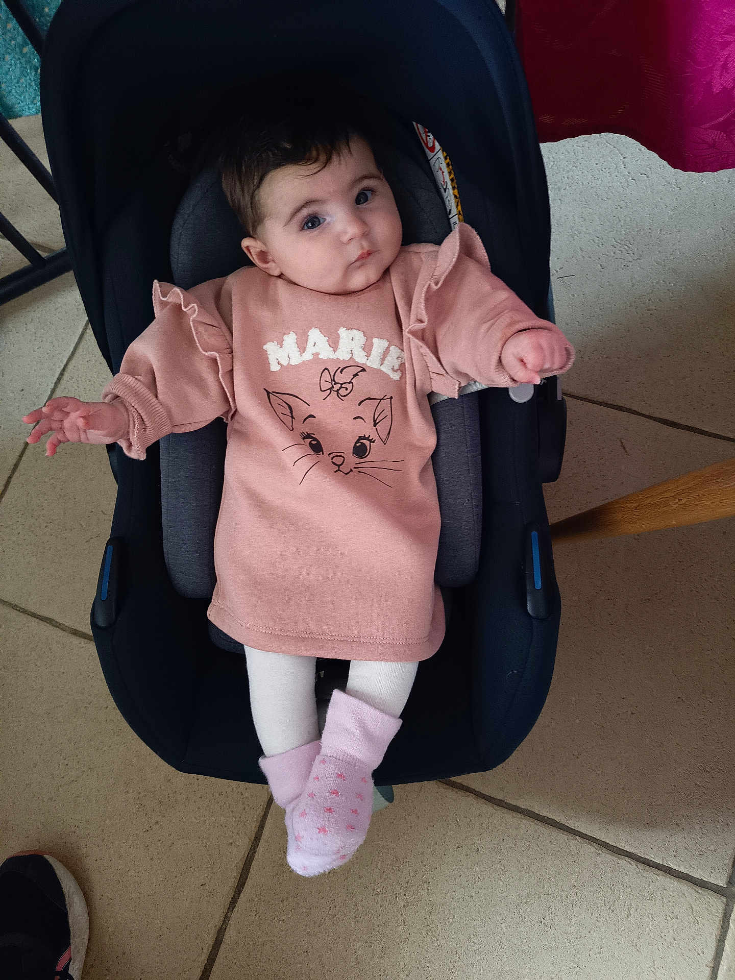 Louise participe au concours pour gagner de l'argent avec cette photo : baby, infant, child, car_seat, pink_sweater, socks, tights, tile_floor, indoor, portrait, cute, blue_eyes, dark_hair, seat, hands, legs, expression, looking_up, clothing, adorable