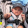 baby, child, stroller, cap, nike, shirt, cartoon, straps, fabric, cute, chubby_cheeks, outdoor, person, infant, seat, baby_clothing, summer, legs, hands, portrait
