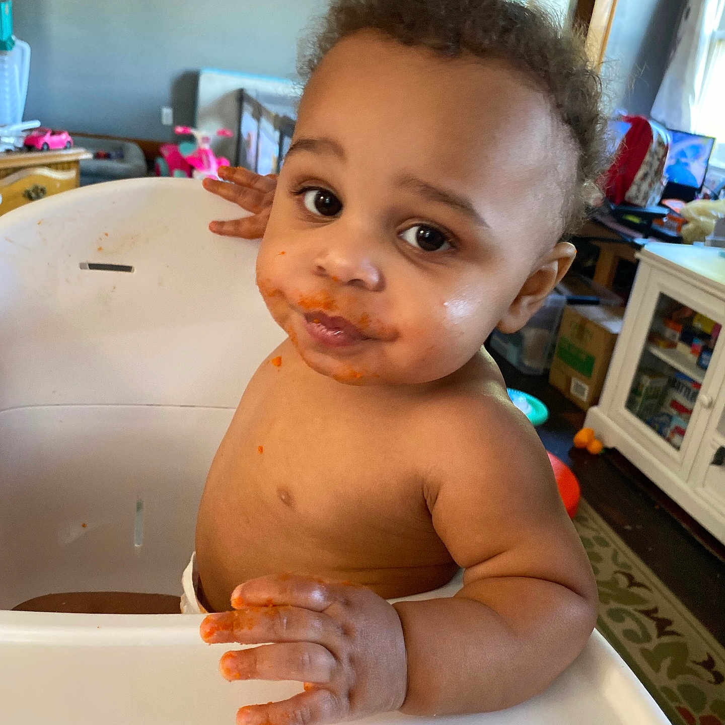 Demitruis J joined the competition — help win amazing prizes! brown_skin, cabinet, carpet, child, curly_hair, curtain, cute, expression, food, furniture, hand, high_chair, indoor, looking_at_camera, messy_face, room, table, toddler, toy, window