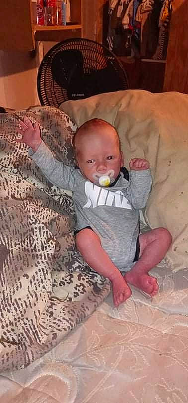 Levi is registered to the contest to win money with this photo: baby, baby_toddler_clothing, bedding, cheek, child, comfort, couch, facial_expression, finger, flooring, fun, head, iris, lap, linens, person, sitting, skin, textile, toddler