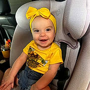 Macey is registered to the contest to win money with this photo: baby, car, car_seat, child, denim_shorts, eyes, face, family, happy, headband, indoors, infant, passenger, photography, portrait, sitting, smiling, vehicle, yellow_bow, yellow_shirt