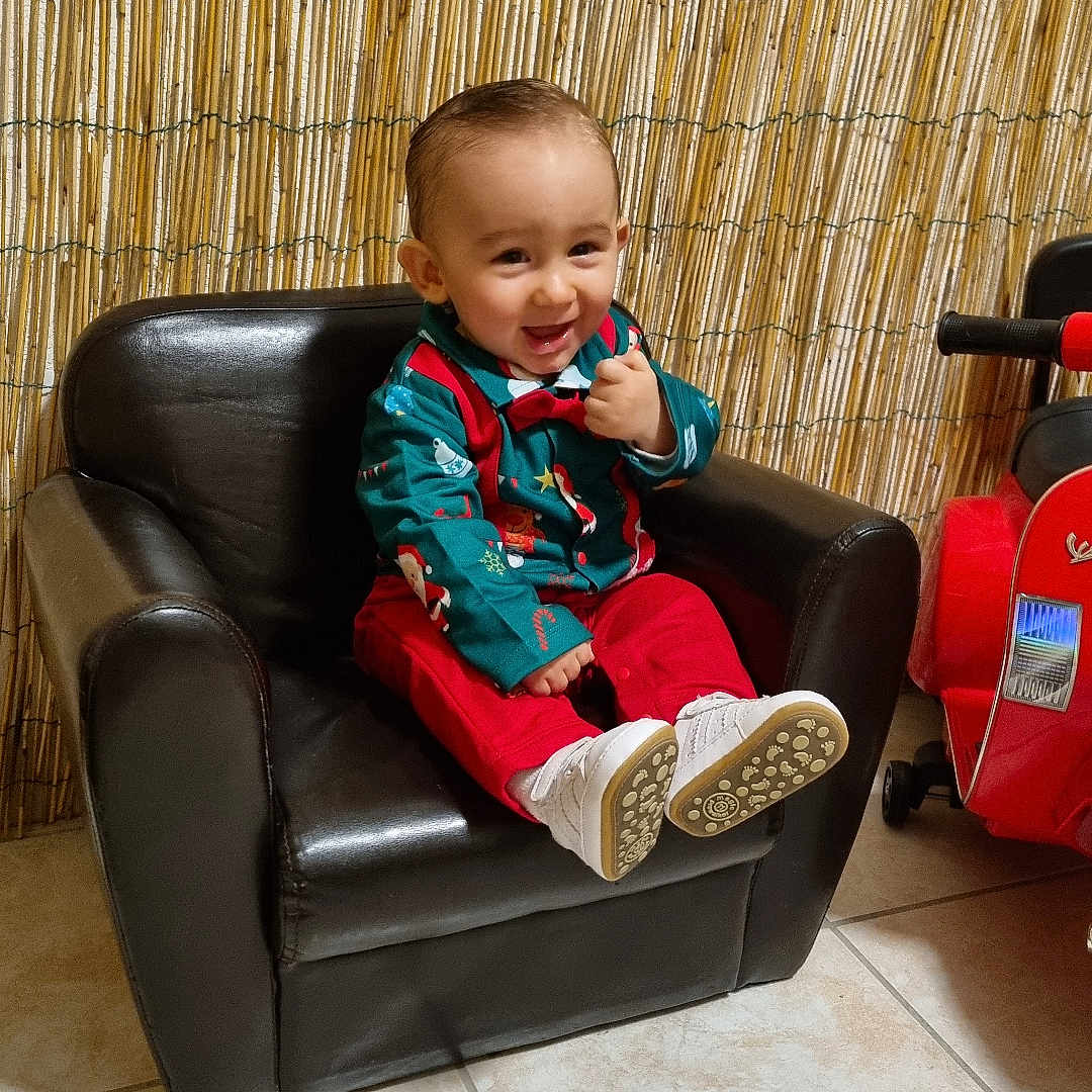 Willem participe au concours pour gagner de l'argent avec cette photo : baby, bamboo_screen, black_leather, chair, child, cute, festive_clothing, footwear, green_shirt, happy, indoor, person, playful, red_pants, sitting, smile, thumbs_up, tile_floor, toddler, toy_car