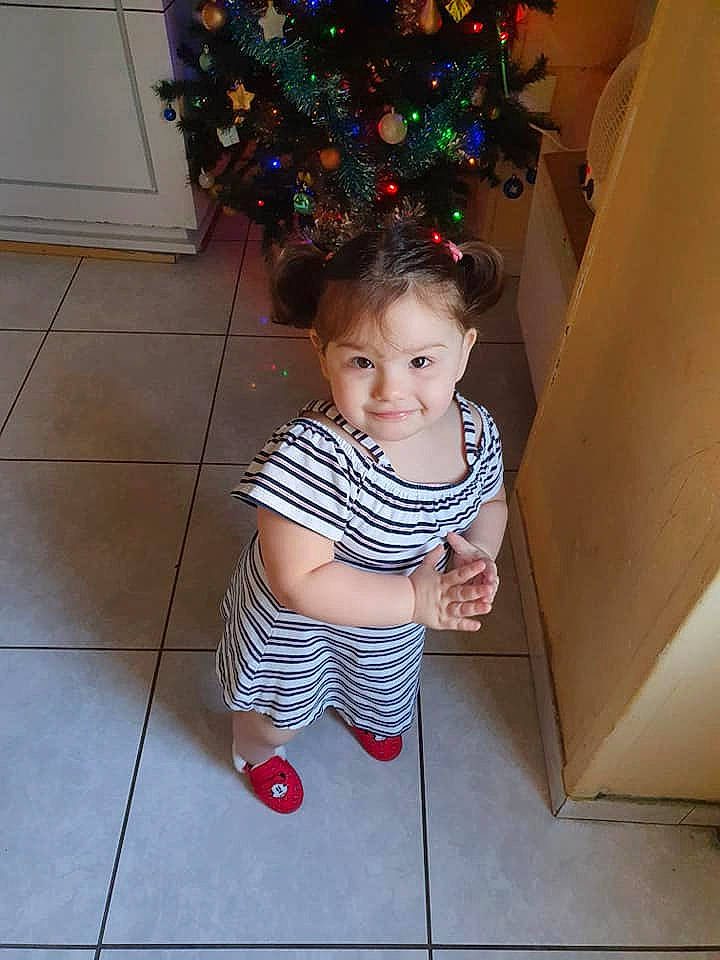 Tiana a rejoint le concours — aidez-le/la à gagner de superbes lots ! baby, baby_toddler_clothing, child, christmas_decoration, christmas_eve, christmas_ornament, christmas_tree, eye, floor, flooring, foot, holiday, holiday_ornament, human, interior_design, joy, ornament, person, shoe, tile