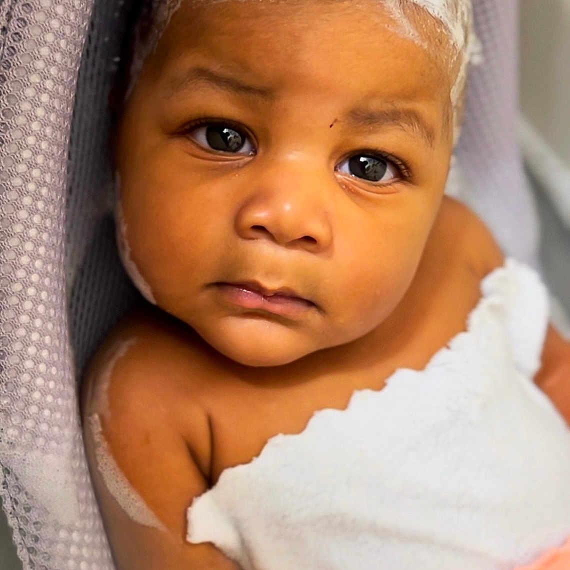 Nazaiah is registered to the contest to win money with this photo: baby, bathing, blonde, bodypart, bonnet, clothing, crying, face, frown, hair, happy, hat, head, person, photography, portrait, sad, shoulder, skin, smile
