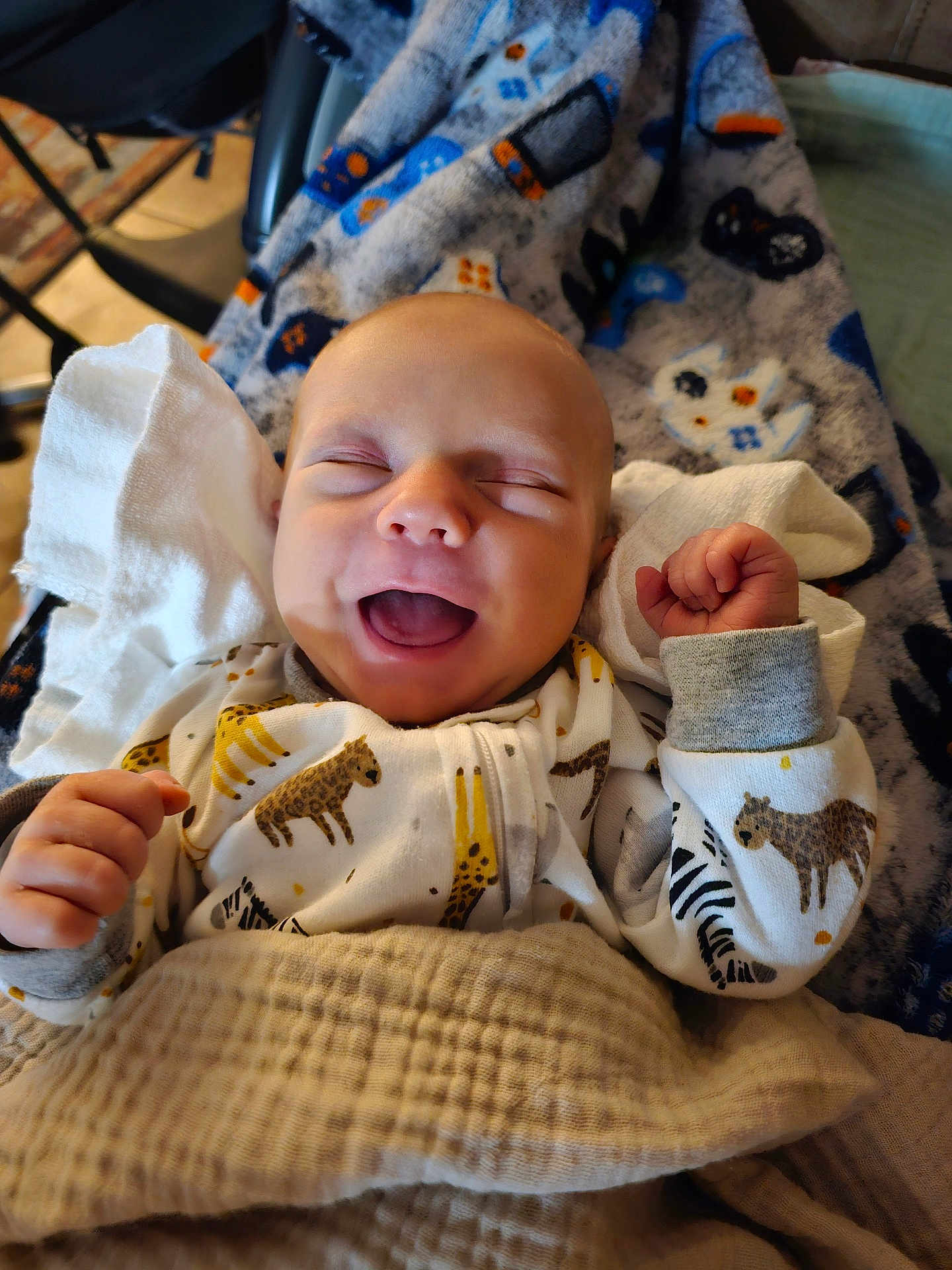 Silas is registered to the contest to win money with this photo: baby, smiling, laughing, blanket, pajamas, animal_print, cozy, infant, happy, cute, child, sleepwear, soft_lighting, indoors, closeup, face, hands, newborn, comfort, resting