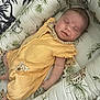baby, sleeping, infant, yellow_outfit, bassinet, animal_print, jungle_theme, cozy, cute, child, padded, soft, peaceful, resting, newborn, portrait, indoors, blanket, patterned, smiling