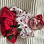 baby, smiling, red_skirt, heart_pattern, headband, red_bow, rose, lying_down, blanket, cute, happy, infant, clothing, soft_texture, portrait, young_child, celebration, adorable, closeup, person