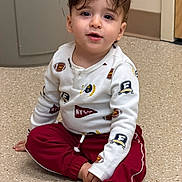 Adam joined the competition — help win amazing prizes! boy, brown_hair, child, close_up, cross_legged, curly_hair, door, fashion, floor, football, hallway, indoors, long_sleeves, portrait, red_pants, sitting, smiling, sportswear, toddler, white_shirt