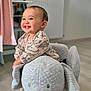 Tommy participe au concours pour gagner de l'argent avec cette photo : baby, child, smiling, plush_toy, elephant, rocker, indoor, floor, clothing, dinosaur_print, happy, person, furniture, radiator, sock, wooden_floor, cute, infant, toy, room