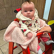 Ivory-Anne joined the competition — help win amazing prizes! baby, child, high_chair, blanket, hand, hoodie, minnie_mouse, clothing, indoor, floor, tile, door, wooden_door, person, pink, orange, seated, cute, infant, warm