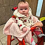 baby, child, high_chair, blanket, hand, hoodie, minnie_mouse, clothing, indoor, floor, tile, door, wooden_door, person, pink, orange, seated, cute, infant, warm