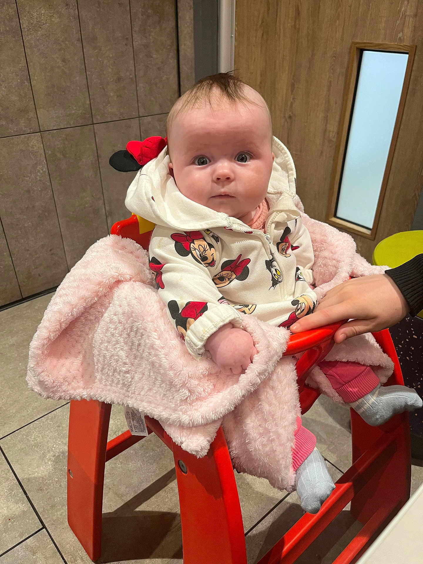 Ivory-Anne joined the competition — help win amazing prizes! baby, child, high_chair, blanket, hand, hoodie, minnie_mouse, clothing, indoor, floor, tile, door, wooden_door, person, pink, orange, seated, cute, infant, warm