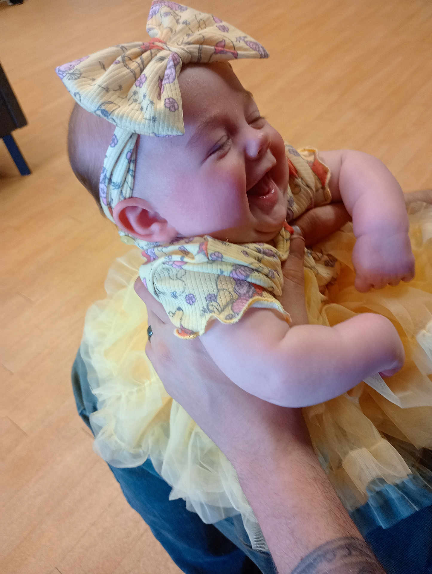 Kendrie is registered to the contest to win money with this photo: baby, child, laughing, smiling, tutu, dress, bow, headband, cute, happy, infant, person, holding, hand, tattoo, arm, indoor, floor, clothing, joy