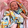 baby, blanket, colorful, smiling, happy, infant, wrapped, soft, pink, fabric, cute, child, lying_down, portrait, indoor, cozy, playful, clothing, face, expression