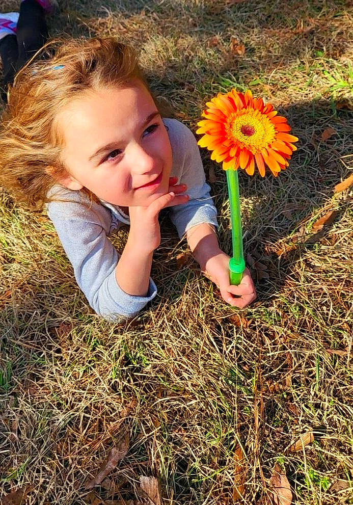 Cassie Flo is registered to the contest to win money with this photo: annual_plant, child, field, flower, fun, grass, happy, joy, landscape, meadow, people_in_nature, person, petal, plant, prairie, smile, soil, spring, sunlight, t_shirt