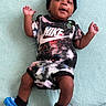 Jasaiah is registered to the contest to win money with this photo: baby, infant, child, smiling, nike, clothing, hat, socks, lying_down, happy, cute, portrait, one_person, indoors, textile, fabric, playful, skin, feet, hands