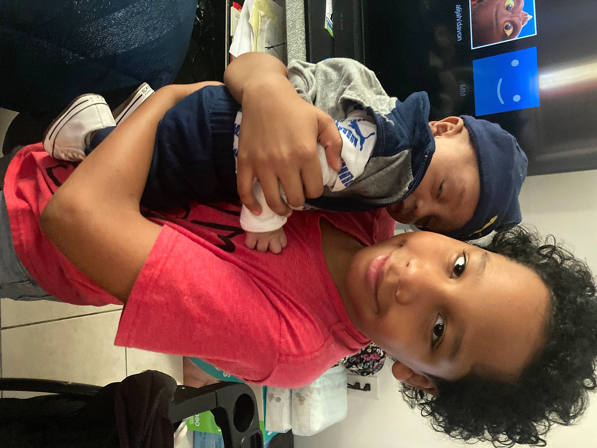 Alijah is registered to the contest to win money with this photo: abdomen, bag, black_hair, chest, child, elbow, event, eyelash, eyewear, fun, headwear, human_leg, joint, joy, luggage_and_bags, mouth, muscle, person, room, television