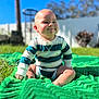 Layla joined the competition — help win amazing prizes! baby, child, outdoor, green_blanket, grass, sunlight, smile, cheeks, striped_clothing, onesie, sitting, yard, fence, tree, happy, cute, portrait, infant, sunny, face