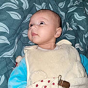 Emma participe au concours pour gagner de l'argent avec cette photo : baby, infant, face, pacifier_clip, blanket, blue_clothing, cream_clothing, patterned_blanket, lying_down, curious_expression, young_child, human, indoors, soft_texture, sleepwear, cute, baby_garment, head, skin, eyes