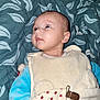 baby, infant, face, pacifier_clip, blanket, blue_clothing, cream_clothing, patterned_blanket, lying_down, curious_expression, young_child, human, indoors, soft_texture, sleepwear, cute, baby_garment, head, skin, eyes