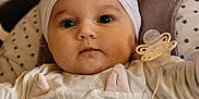 Emma participe au concours pour gagner de l'argent avec cette photo : baby, headband, bow, pacifier, beads, clothing, cushion, blanket, face, infant, person, cute, indoors, portrait, child, soft_toys, seated, closeup, comfortable, expression
