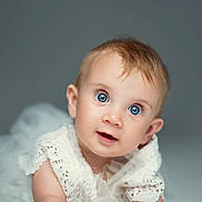 Adèle participe au concours pour gagner de l'argent avec cette photo : baby, blue_eyes, curious, face, lace, white_clothing, portrait, studio, soft_focus, infant, cute, child, closeup, head, smiling, young, person, background, expression, skin