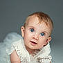 baby, blue_eyes, curious, face, lace, white_clothing, portrait, studio, soft_focus, infant, cute, child, closeup, head, smiling, young, person, background, expression, skin
