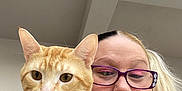Tiger is registered to the contest to win money with this photo: cat, orange_tabby, collar, woman, glasses, portrait, selfie, indoor, face, person, pet, animal, hair, expression, closeup, casual, feline, muzzle, whiskers, nose