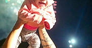 Alice is registered to the contest to win money with this photo: arm, baby, celebration, child, clothing, darkness, fireworks, happy, holding, jacket, joy, light, night, outdoor, pants, person, portrait, sandals, smile, tattoo