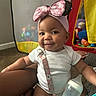baby, infant, smile, headband, pink_bow, milk_bottle, toy, play_tent, carpet, indoor, child, cute, happy, clothing, person, seated, pacifier_clip, skin, face, baby_toy