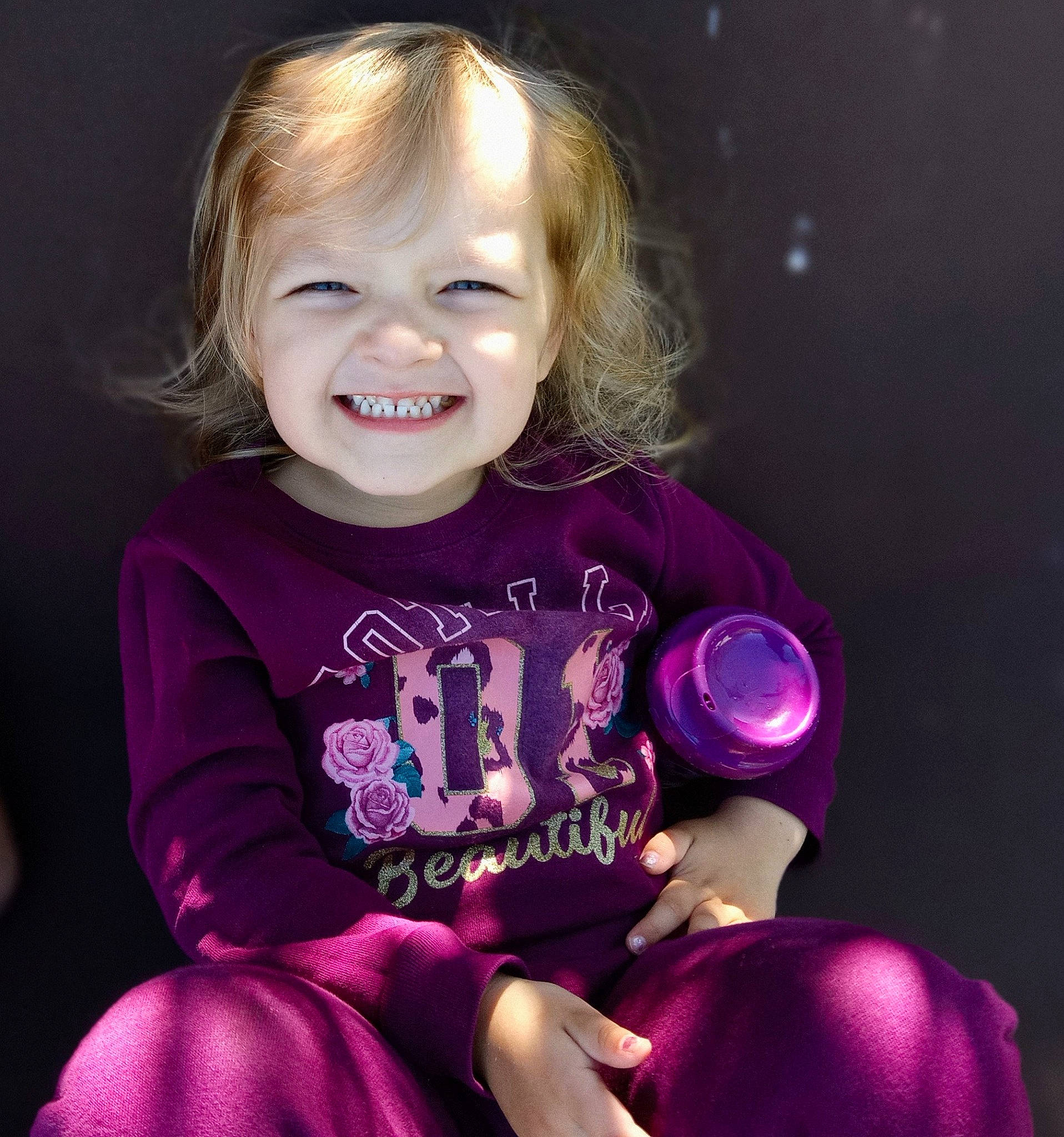 Ellie is registered to the contest to win money with this photo: arm, baby, baby_toddler_clothing, cheek, cool, face, fun, happy, human_body, iris, joy, lip, magenta, person, pink, purple, skin, sleeve, smile, standing