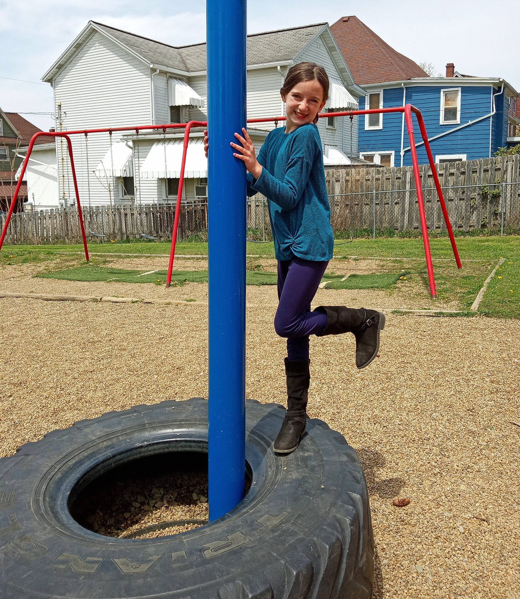 Kaelyn is registered to the contest to win money with this photo: automotive_tire, balance, building, city, composite_material, electric_blue, fun, joy, leisure, outdoor_play_equipment, person, playground, recreation, sky, smile, soil, synthetic_rubber, t_shirt, tire, tire_care