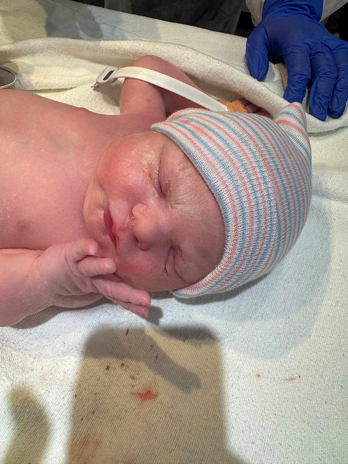 Irene joined the competition — help win amazing prizes! newborn, baby, sleeping, hat, striped_hat, hospital, towel, gloved_hand, medical, infant, skin, hand, peaceful, closeup, person, child, newborn_baby, healthcare, delivery, resting