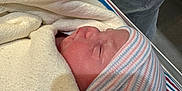 Irene joined the competition — help win amazing prizes! newborn, baby, blanket, hospital, bassinet, hat, striped_hat, sleeping, infant, person, gloved_hand, medical, bed, fabric, resting, closeup, skin, cute, peaceful, wrapped