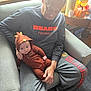 baby, candle, casual_clothing, chair, child, cozy, cute, fall_decor, family, football_shirt, home, hood, indoor, man, person, person_holding_baby, pumpkin, sweatpants, turkey_costume, window