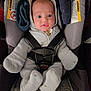 baby, infant, car_seat, onesie, hooded_clothing, straps, safety, seat, child, young, cute, indoor, person, face, wide_eyes, clothing, seatbelt, warning_label, soft, expression