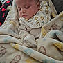 Toby is registered to the contest to win money with this photo: baby, sleeping, blanket, bib, cute, cozy, infant, soft, patterned, heart_pattern, clothing, rest, peaceful, indoors, portrait, child, nap, comfort, toddler, home