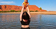 Juniper joined the competition — help win amazing prizes! baby, woman, water, lake, outdoor, sky, red_rocks, cliffs, nature, child, holding, playful, sunlight, summer, recreation, happy, person, back_view, parent, lifting