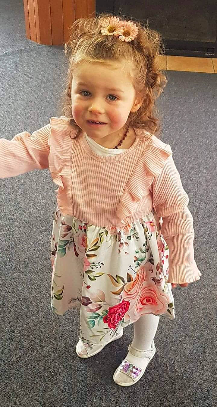 Lilly-anne is registered to the contest to win money with this photo: baby_toddler_clothing, cheek, child, day_dress, dress, face, flooring, hairstyle, happy, iris, joint, one_piece_garment, outerwear, pattern, person, pink, skin, sleeve, smile, standing
