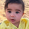 Persephone is registered to the contest to win money with this photo: baby, child, infant, portrait, close_up, face, eyes, brown_hair, yellow_clothing, outdoor, beach, sand, sunlight, windblown_hair, wide_eyed, open_mouth, sitting, photography, adorable, toddler