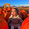 Persephone is registered to the contest to win money with this photo: baby, child, pumpkin_patch, pumpkins, autumn, harvest, farm, outdoor, portrait, sitting, baby_hat, knit_clothing, sweater, tights, face, eyes, looking_at_camera, sunlight, blue_sky, rustic_background