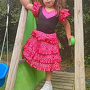 Angel a rejoint le concours — aidez-le/la à gagner de superbes lots ! child, girl, playground, slide, dress, pink, black, polka_dots, wooden_structure, outdoor, grass, sneakers, sock, curly_hair, play, toy, green_slide, confident, pose, nature