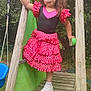 child, girl, playground, slide, dress, pink, black, polka_dots, wooden_structure, outdoor, grass, sneakers, sock, curly_hair, play, toy, green_slide, confident, pose, nature