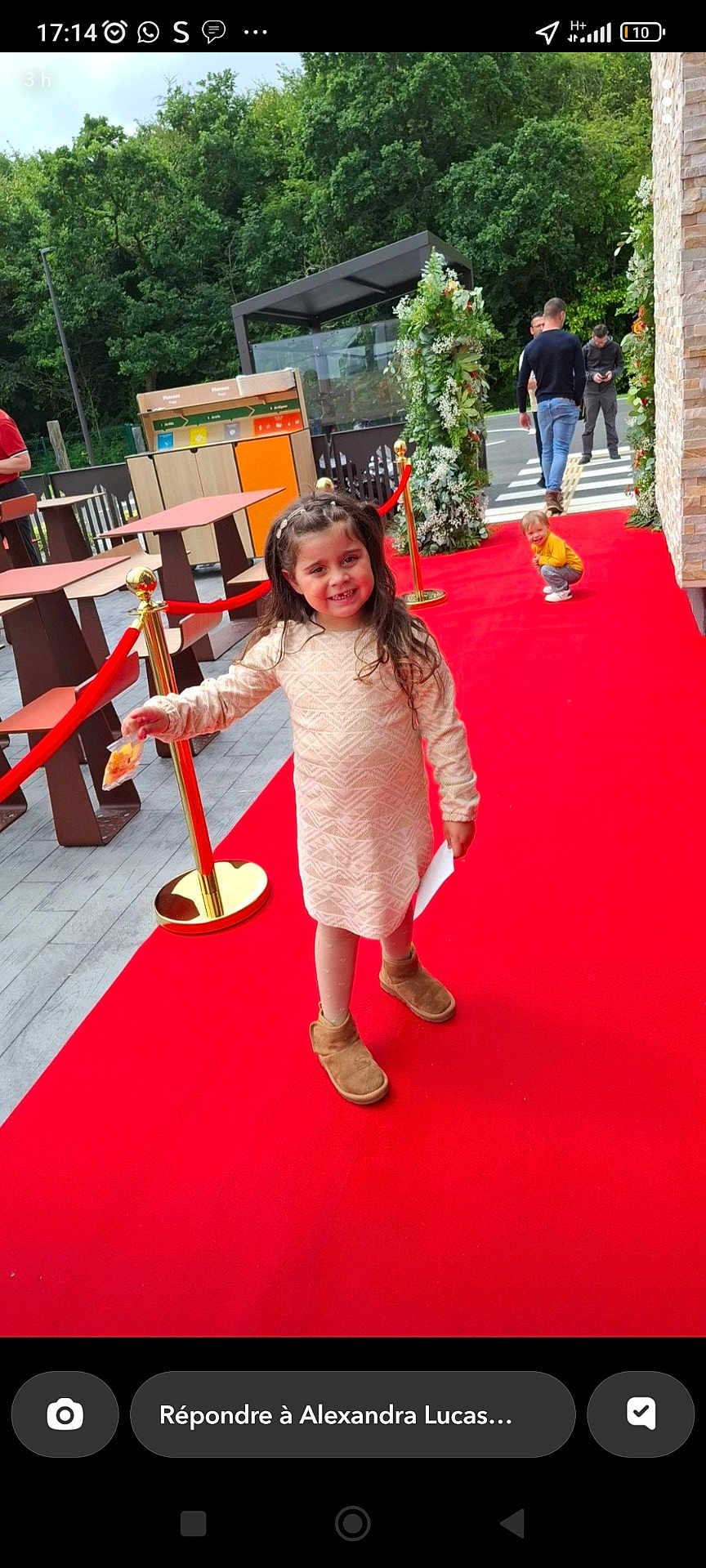 Angel a rejoint le concours — aidez-le/la à gagner de superbes lots ! child, girl, red_carpet, outdoor, smiling, boots, dress, snack, paper, greenery, decorations, people, adult, walking, pavement, fence, table, chair, daylight, event
