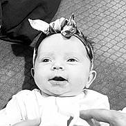 Delilah joined the competition — help win amazing prizes! baby, infant, headband, smiling, face, eyes, mouth, hands, white_clothing, texture, fabric, portrait, cute, child, young, person, indoor, black_and_white, closeup, happy