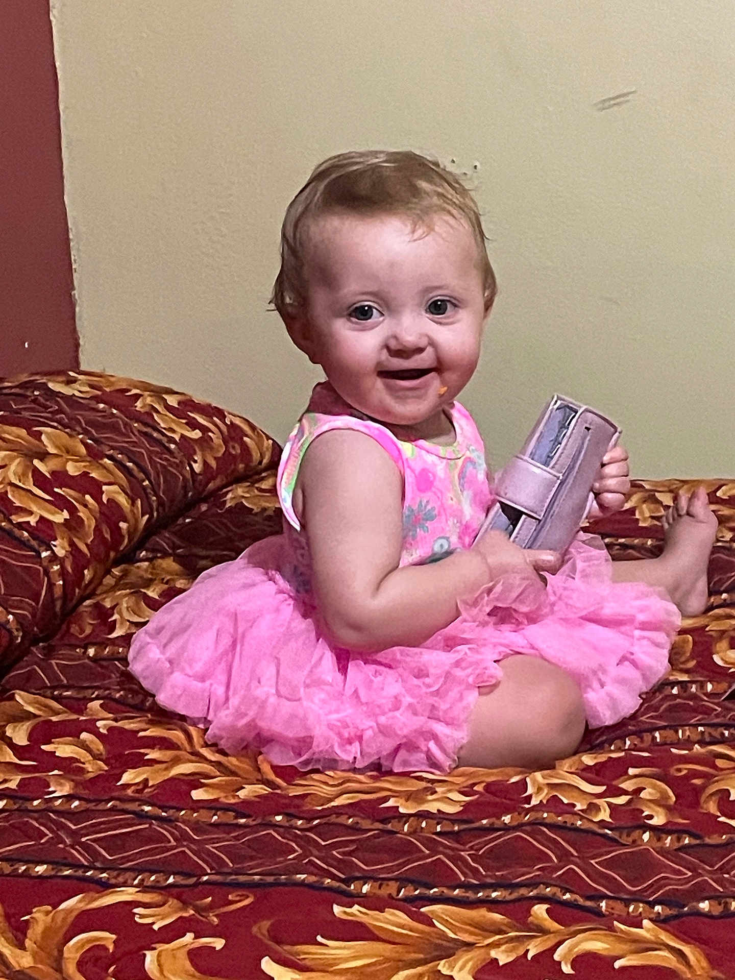 Oaklynn is registered to the contest to win money with this photo: baby, child, pink_dress, smiling, sitting, bed, purse, indoor, cute, infant, face, happy, toddler, patterned_bedspread, furniture, person, young_child, playful, holding_object, portrait